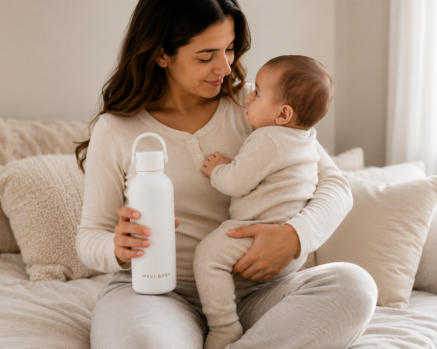 Mother holding baby and Mavi Baby Thermos on couch